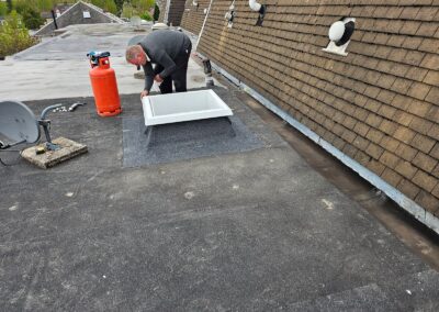 Roofer fitting a flat roof around a rooflight