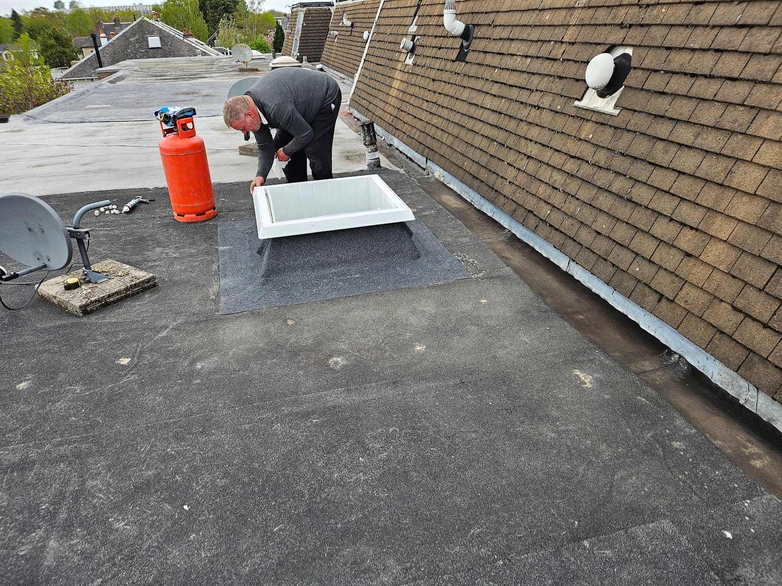Roofer fitting a flat roof around a rooflight