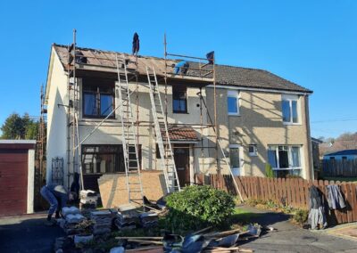 House under scaffolding during roughcasting work