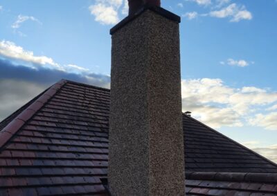 Roughcast chimney stack on a tiled roof